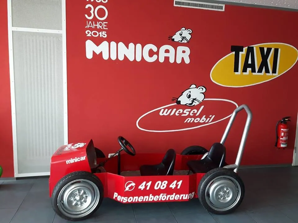 Rote Seifenkiste mit Minicar-Aufschrift vor einer Wand mit dem Schriftzug 30 Jahre Minicar 2015